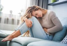 Woman holding her stomach in pain on a sofa