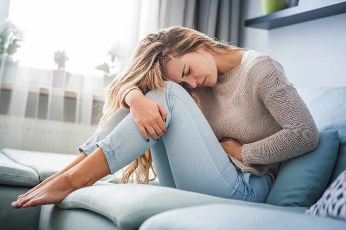 Woman holding her stomach in pain on a sofa