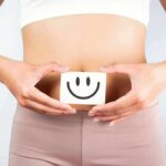 Gut Hack That Lowers Cholesterol and Inflammation torso of person holding smiley card over stomach