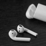 Wireless earbuds with open charging case on dark wood