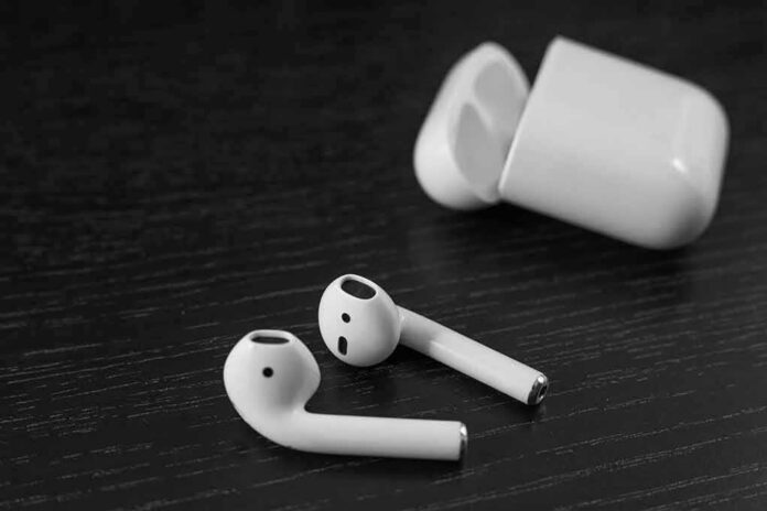 shutterstock_1384825676 Wireless earbuds with open charging case on dark wood