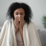 Doctor-Backed Natural Remedies for Colds & Flu Woman wrapped in a blanket blowing her nose