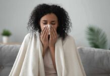 Woman wrapped in a blanket blowing her nose