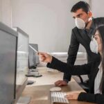 Outbreak Hunters: Understanding the work of epidemiologists Two office workers wearing masks at a computer
