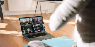 person on yoga mat watching a virtual workout class on a laptop