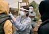 Neck Lump Won’t Quit? Big Red Flag Healthcare worker in PPE examines a patient at an outdoor clinic