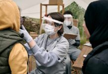 Neck Lump Won’t Quit? Big Red Flag Healthcare worker in PPE examines a patient at an outdoor clinic