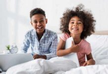 Screen-Time Myth Exposed by Top Doctors two smiling children sitting on a bed