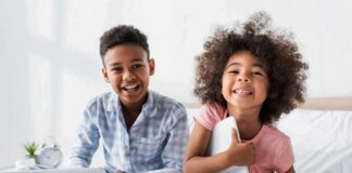 two smiling children sitting on a bed