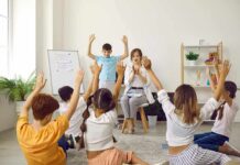 Therapist Blasts ‘Gentle Parenting’ Trend Children raise hands in a classroom circle with teacher clapping