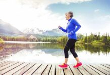 Older woman jogging on a wooden dock by a mountain lake