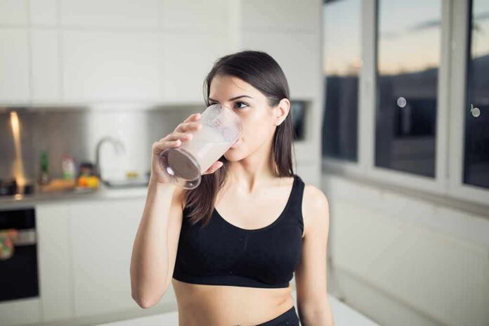 shutterstock_385221889 Woman in sportswear drinking a smoothie in a kitchen