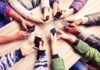 Hands around a table holding smartphones