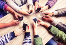 The science of how social media affects mental health Hands around a table holding smartphones