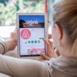 Airbnb Unveils New Rules Limit Checkout Chores Woman using a tablet to view the Airbnb app page