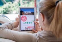 Airbnb Unveils New Rules Limit Checkout Chores Woman using a tablet to view the Airbnb app page