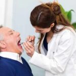 Mouth Bacteria, Mind Slide? Dentist examining an older man's mouth with a dental mirror