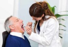 Dentist examining an older man's mouth with a dental mirror