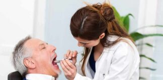 Dentist examining an older man's mouth with a dental mirror