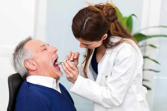 Dentist examining an older man's mouth with a dental mirror