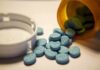 Cardiovascular Risks of Using Adderall Recreationally Blue pills spilled from an orange prescription bottle beside a white cap