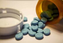 Blue pills spilled from an orange prescription bottle beside a white cap
