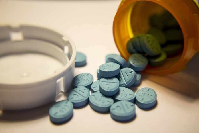 Blue pills spilled from an orange prescription bottle beside a white cap