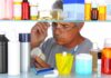 Man reading a pill bottle in a bathroom cabinet