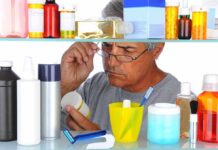 Man reading a pill bottle in a bathroom cabinet