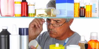 Man reading a pill bottle in a bathroom cabinet